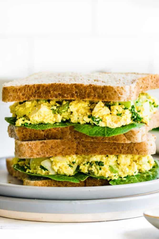 Two tofu egg salad sandwiches stacked on top of eachother