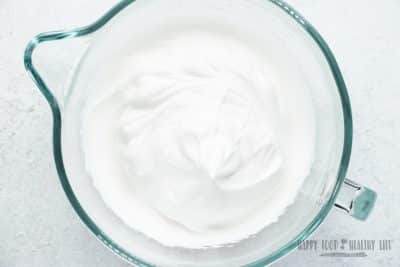 vegan whipped cream that is bright white and thick, in a glass mixing bowl.