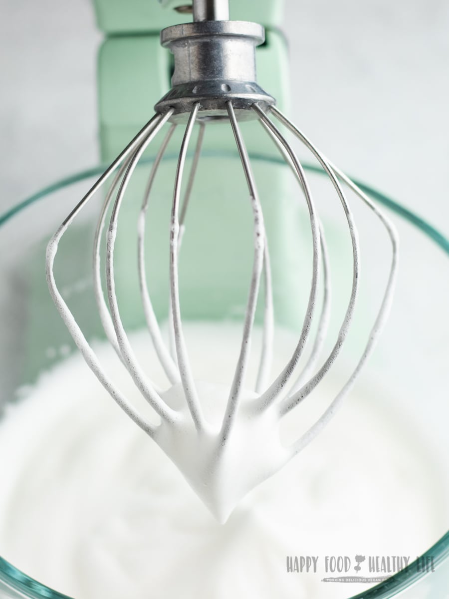 a pale green stand mixer holding a glass bowl of vegan whipped cream mixed with the whisk attachment.