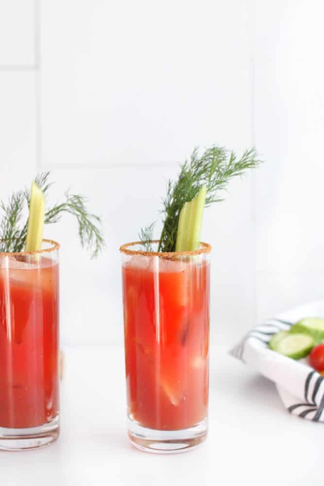 Bloody Mary in a glass garnished with celery, fresh dill, and rimmed with Old Bay seasoning. 