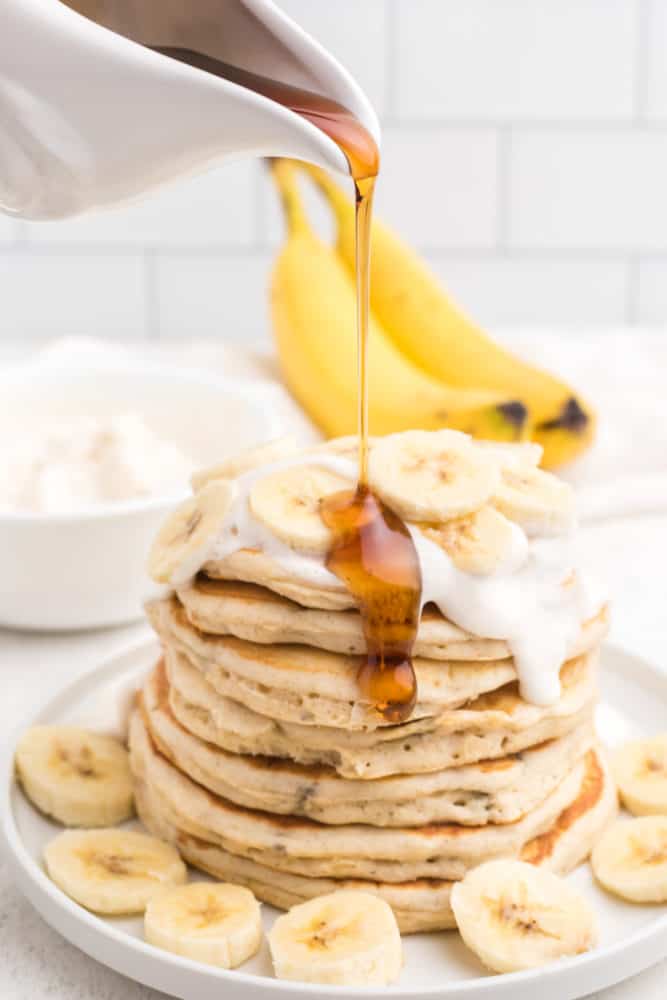 vegan banana pancakes topped with vegan whipped cream and syrup