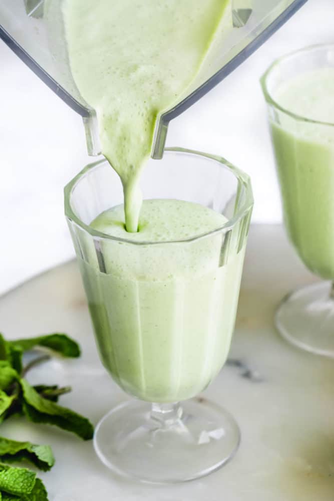 Shamrock Shake being poured from a blender into a tall glass. 