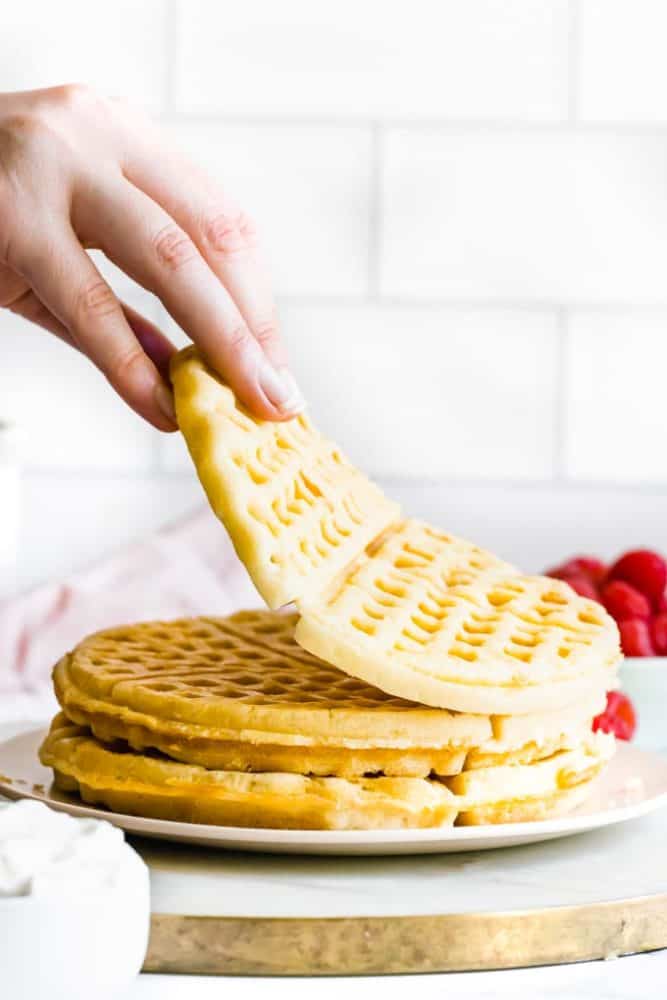 hand picking up one vegan waffle off a stack of waffles