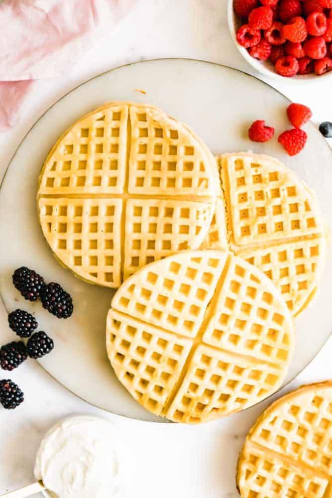 Plate of three plain plant based waffles with raspberries and blackberries on the side. 