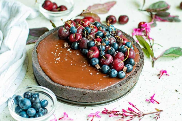 chocolate tart decorated with cherries and blueberries on half. 