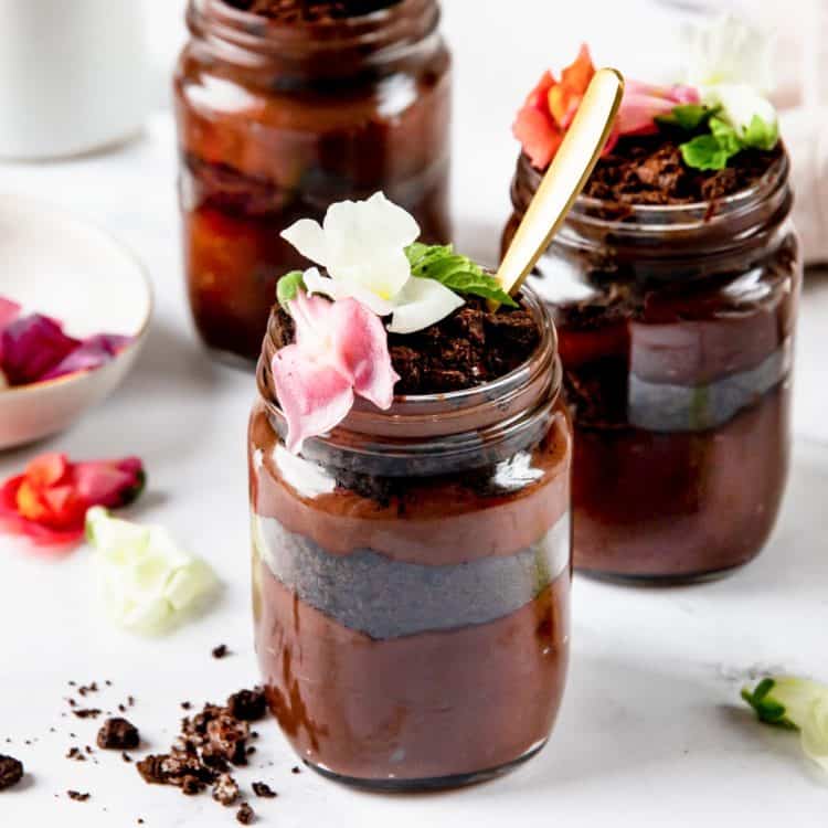 Trio of Vegan dirt cups in mason jars. garnished with edible flowers.