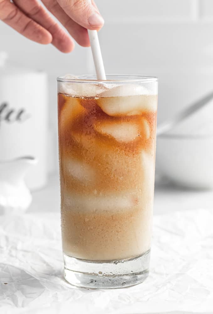 paper straw in a glass of cold brew ice coffee with cream.