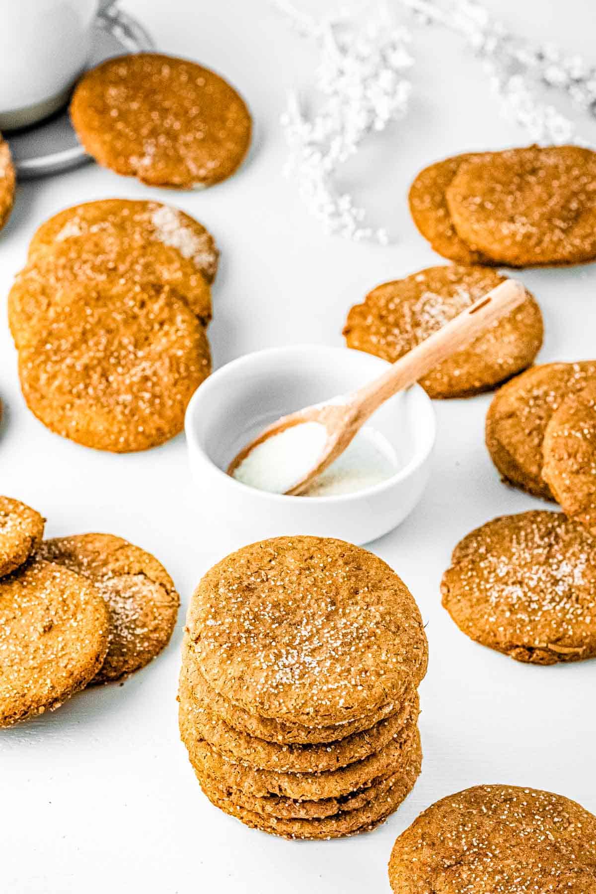beautiful stack of vegan gingerbread cookies next to a bowl of sugar and more cookies