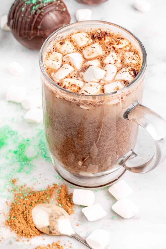 Glass mug of melted vegan hot chocolate bomb and topped with marshmallows.