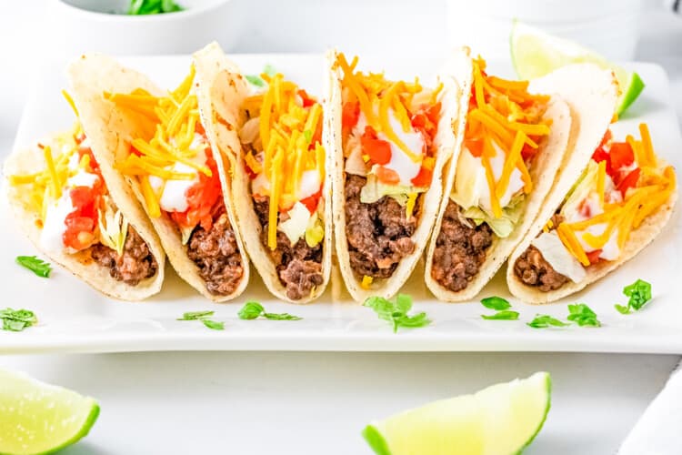 tacos filled and lined up on a white plate on a white background