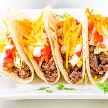 a close up row of vegan tacos on a white plate