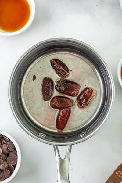 Top view photo of a sauce pan with water and dates in the pan.