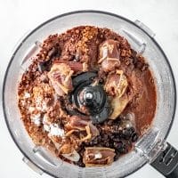 Top view photo of a food processor with the remaining ingredients to make black bean brownies, ready to be processed until smooth.