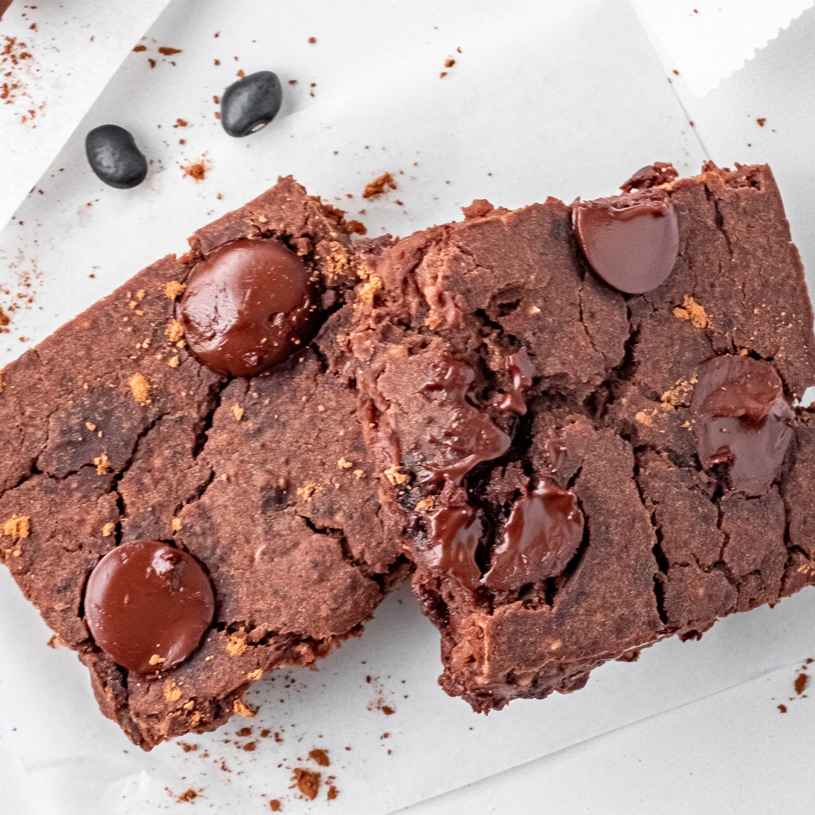 Top view photo of two black bean brownies, on a white plate, ready to enjoy.