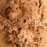 Top view photo of a stand mixer bowl with peanut butter, maple syrup, and chocolate chips all mixed together.