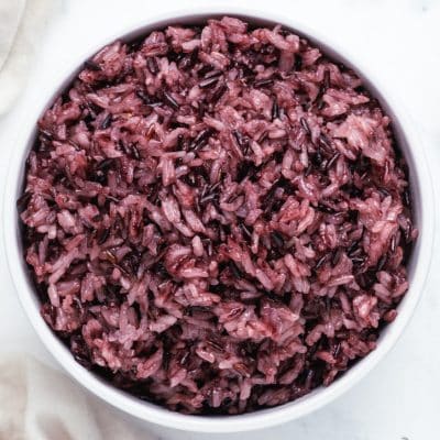 Top view photo of a white bowl filled with purple sticky rice.
