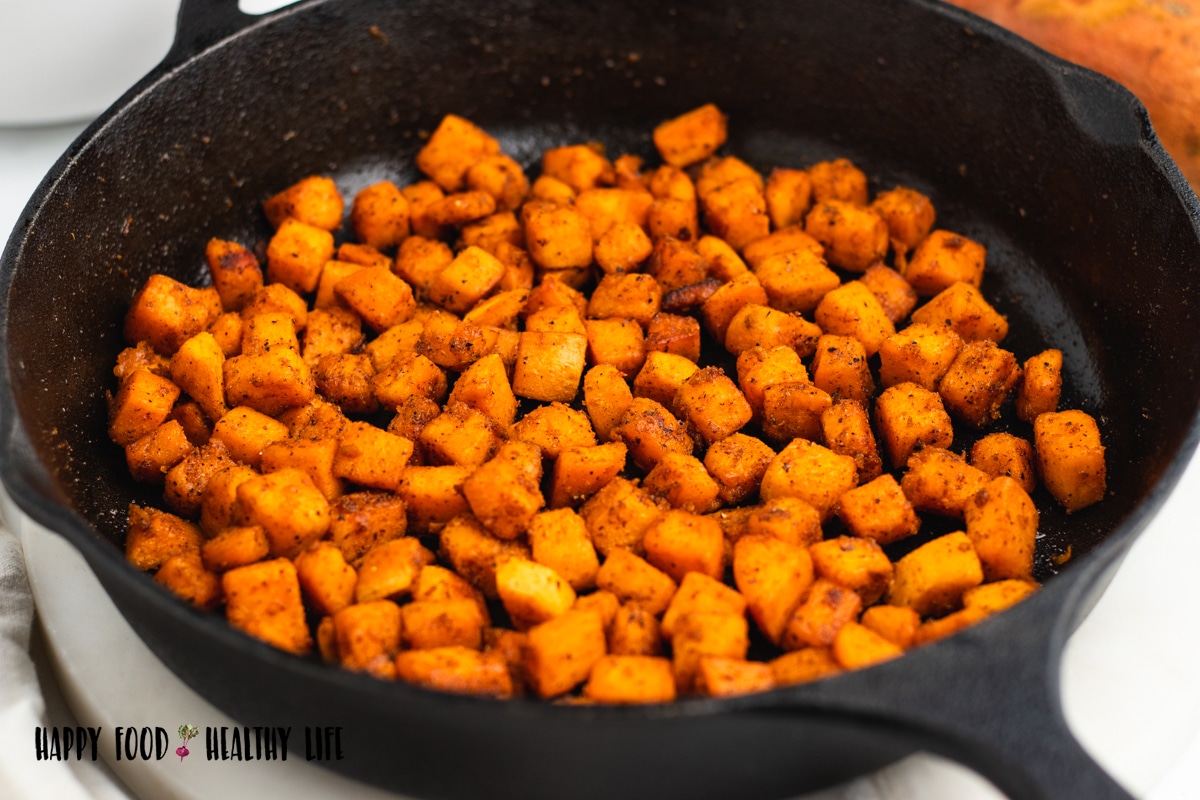 Photo of a cast iron skillet, filled with sauteed sweet potatoes cubes. 