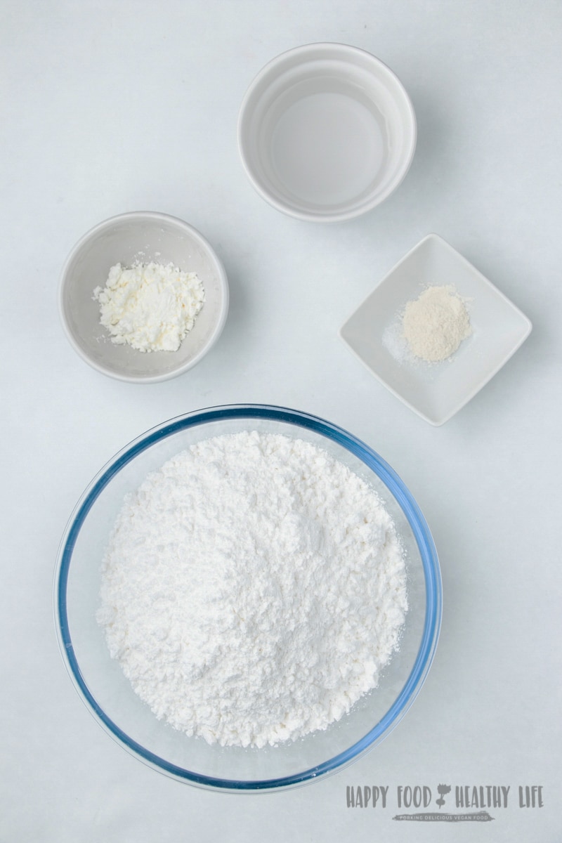 a large clear bowl of powdered sugar. next it are three small bowls, one with cornstarch, one with water, and one with xanthan gum. Photo Credit: Cindy Gordon of HappyFoodHealthyLife.com